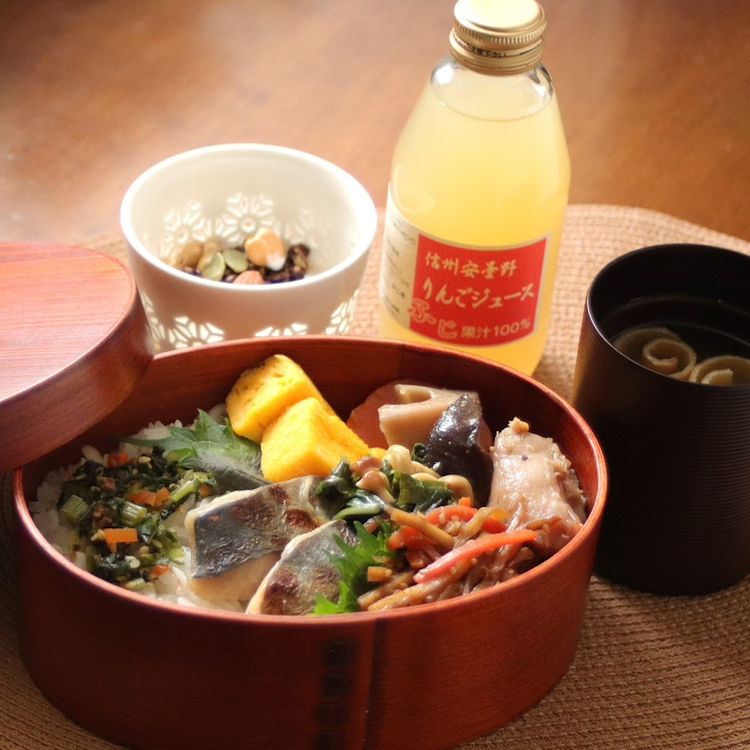 安曇野産のごはんに焼き魚や野菜を詰めたわっぱ弁当。信州味噌の味噌汁と信州産りんごジュースが添えられた、宿の朝食セット